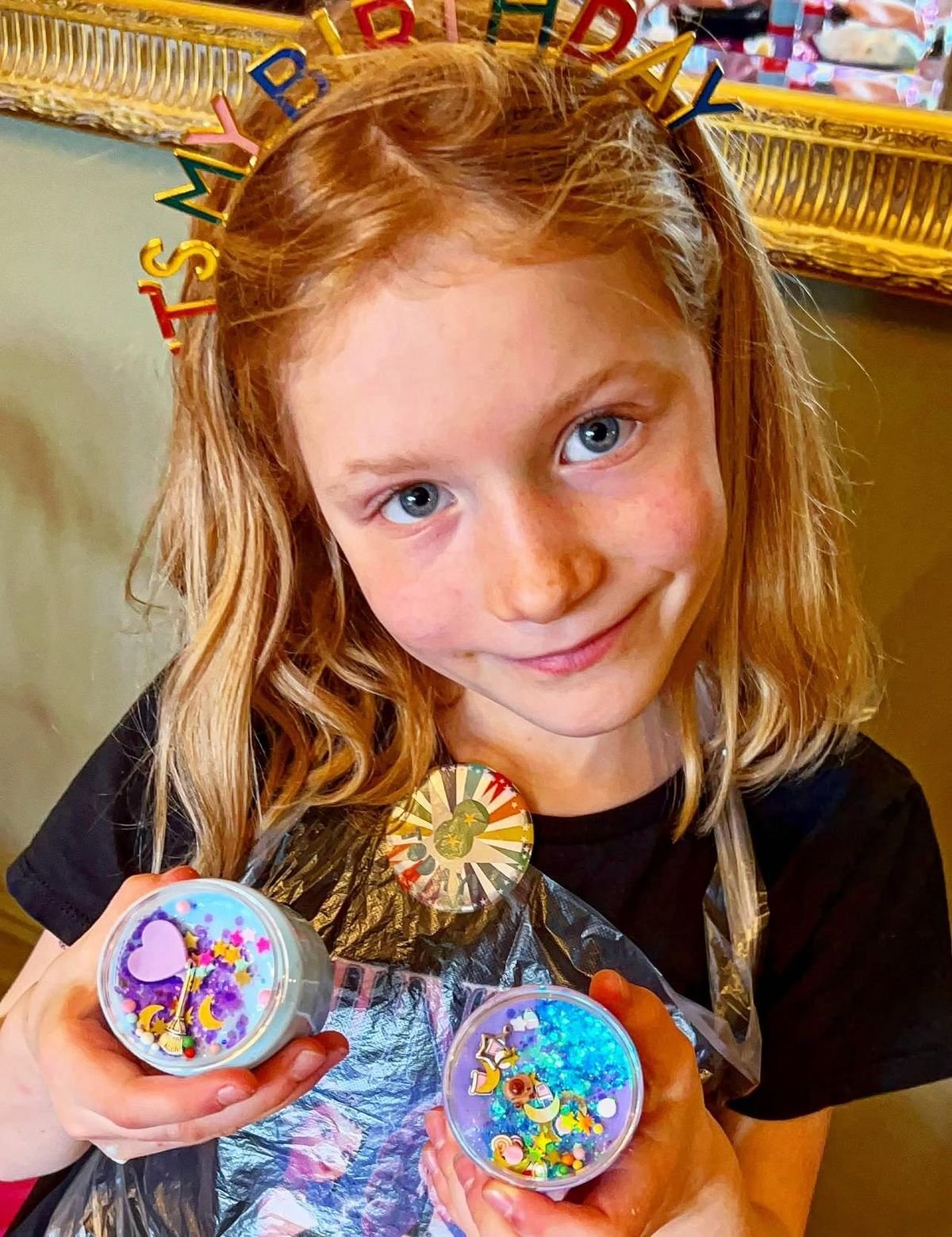 A happy child holding her two Jazzy Slime take-home pots