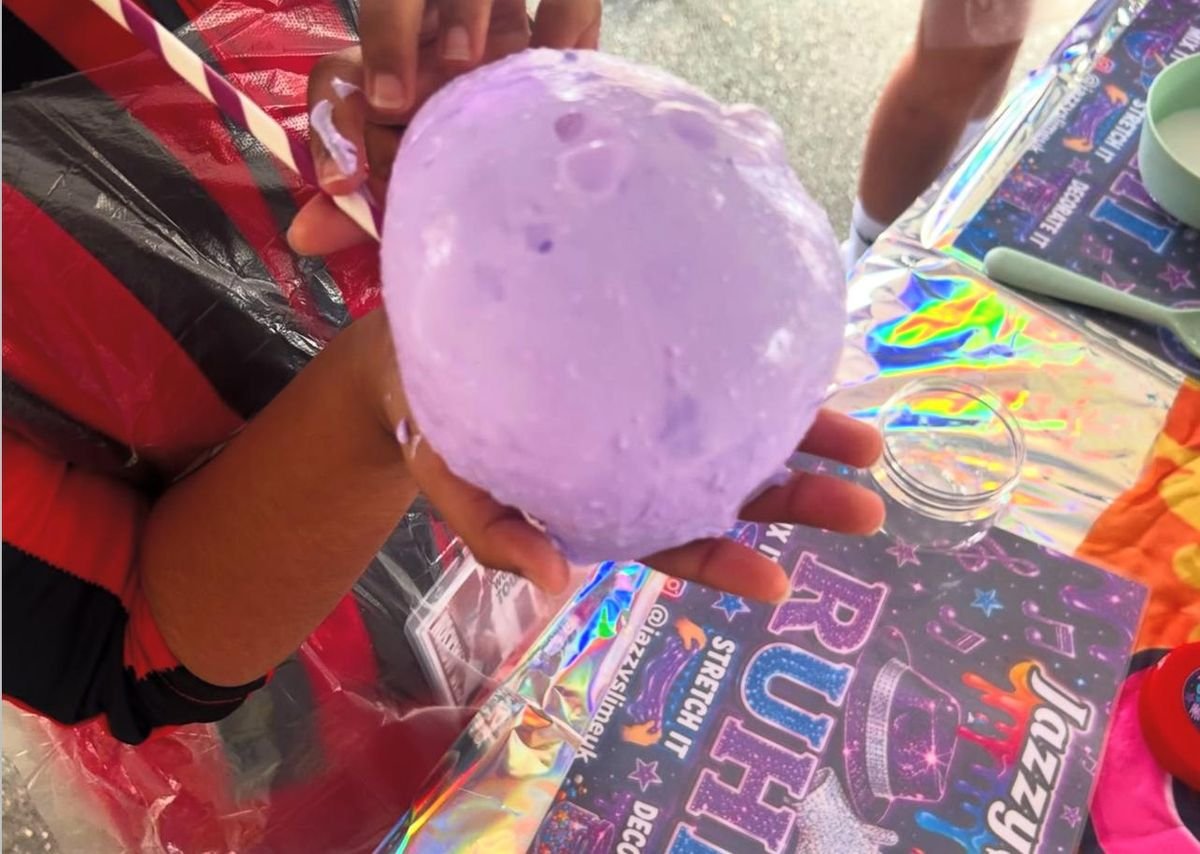 A hand holding a stretch of lilac slime